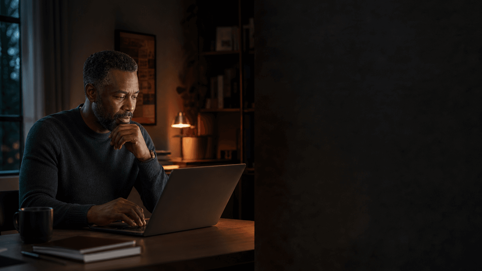 A man thoughtfully reviewing a disease intelligence update on his laptop at home